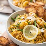 Bowl of lemon shrimp asparagus pasta garnished with lemon slices and toasted baguette.