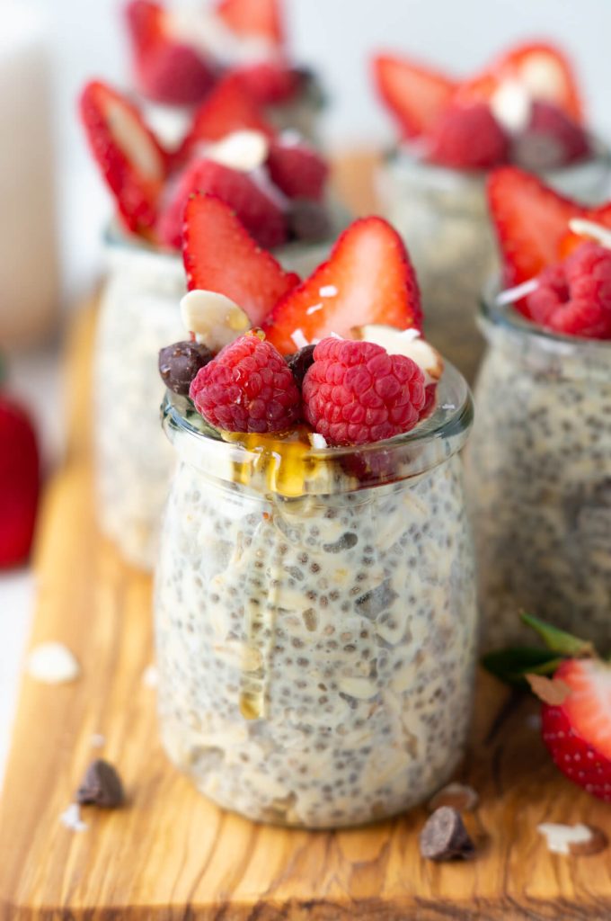 Jar of protein overnight oats topped with berries, chocolate chips, and a drizzle of honey.