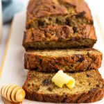 Overhead shot of gluten-free zucchini banana bread with butter and honey and a side of milk.