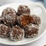 A bowl of peanut butter chocolate bliss balls that have been rolled in shredded coconut.