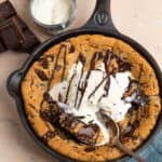 Photo of chocolate chip cookie skillet topped with vanilla ice cream and a melted chocolate drizzle.