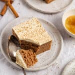 Two plates with a piece of applesauce spice cake sprinkled with cinnamon.