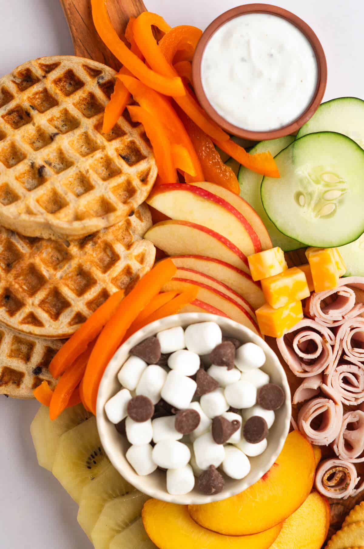 An up close shot of kid-friendly foods arranged on a charcuterie board.