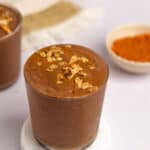 A glass filled with chocolate pumpkin protein shake with a sprinkle of granola on top.