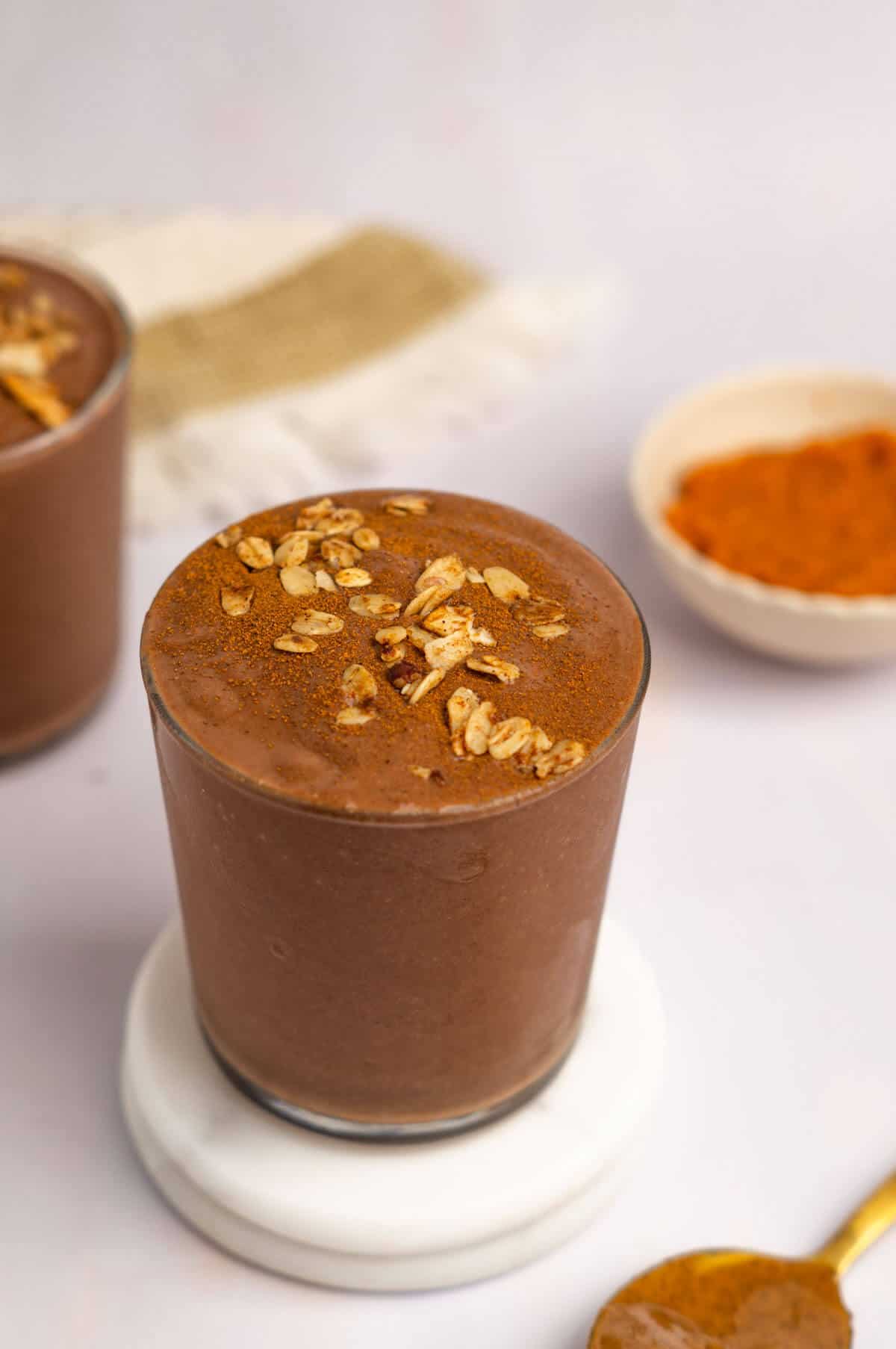 A glass filled with chocolate pumpkin protein shake with a sprinkle of granola on top.