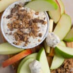 An overhead shot of a bowl of toffee apple dip with sliced apples.