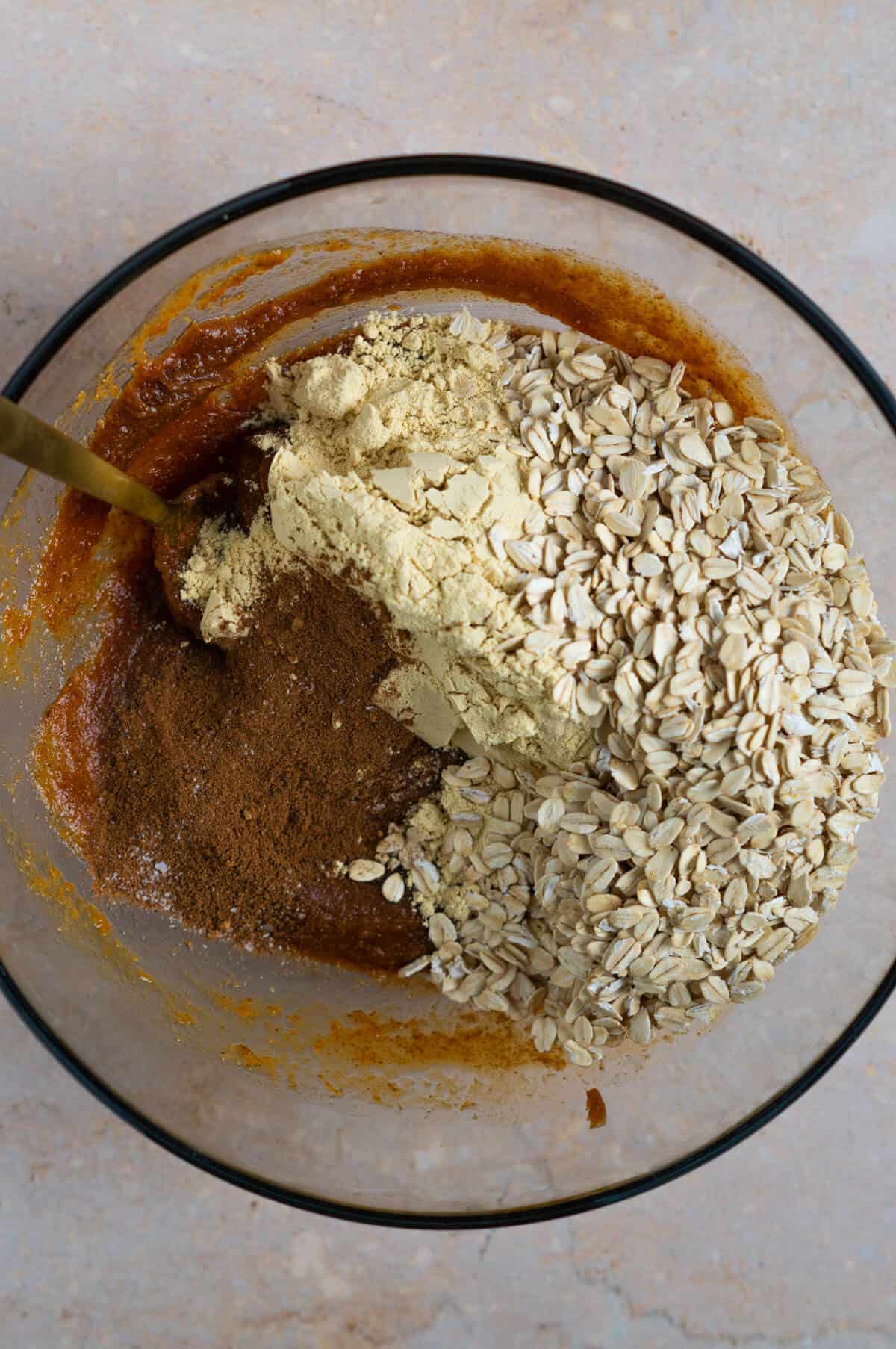 The combined wet ingredients for pumpkin protein balls with oats, salt, pumpkin pie spice, and vanilla protein powder.