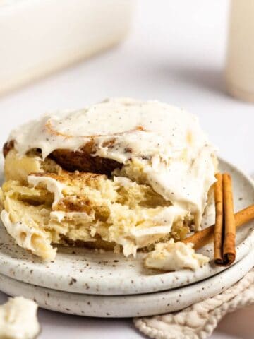 An up close shot of a brown butter cinnamon roll garnished with cinnamon sticks.