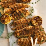 Overhead shot of herb crusted chicken with garnishes of thyme and caramelized onions.