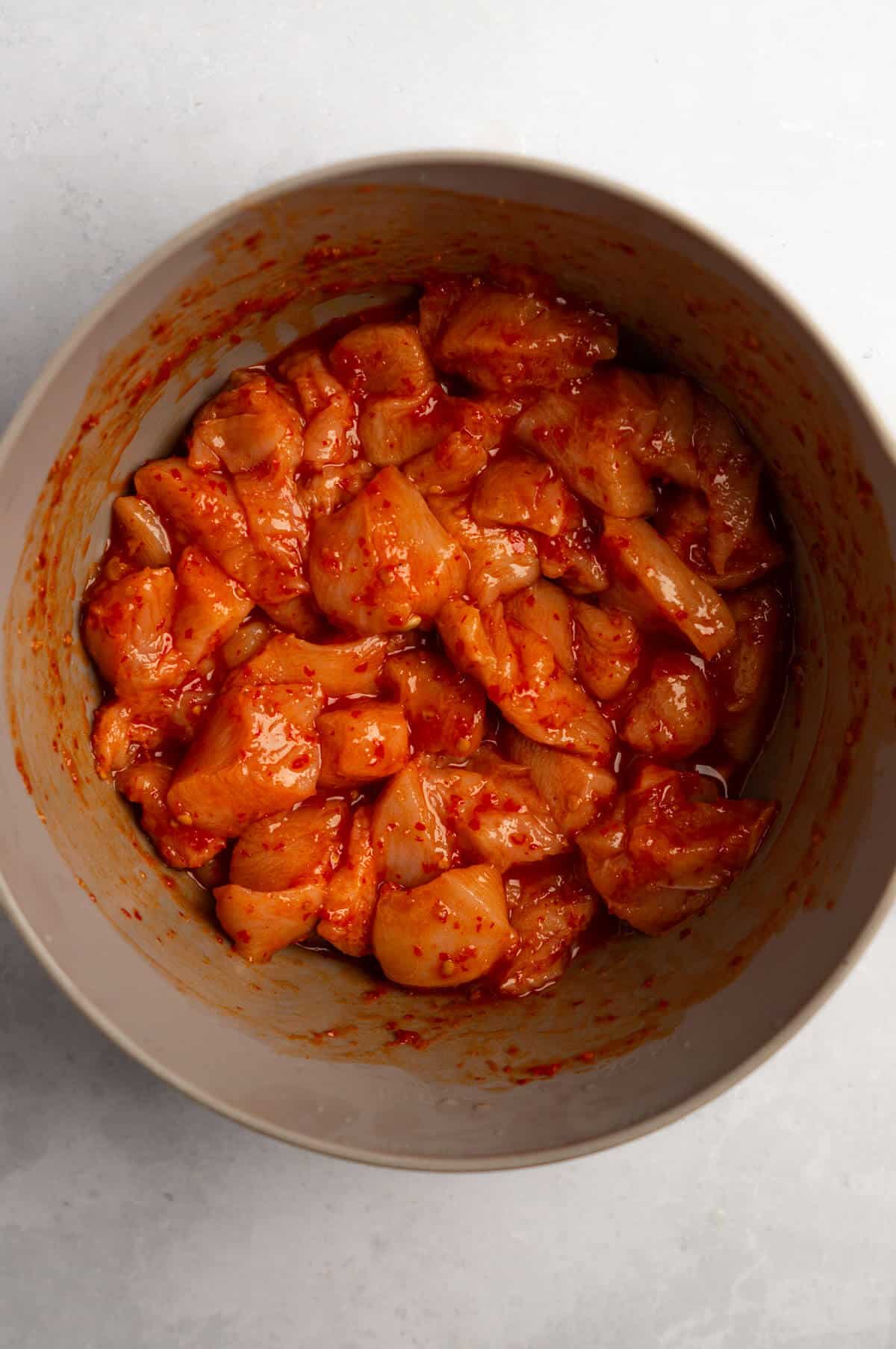 A bowl with marinating honey harissa chicken.