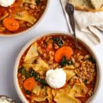An overhead shot of two bowls of turkey lasagna soup with bread on the side.