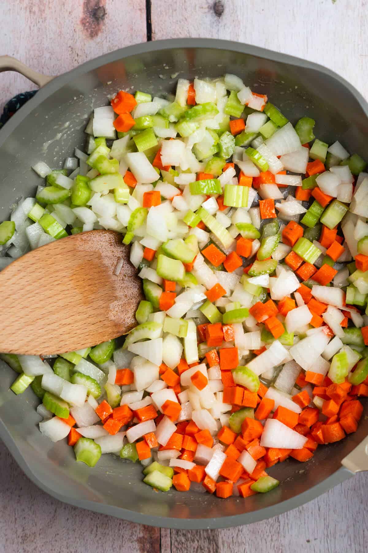 A large skillet with melted butter and chopped celery, onion, and carrot.
