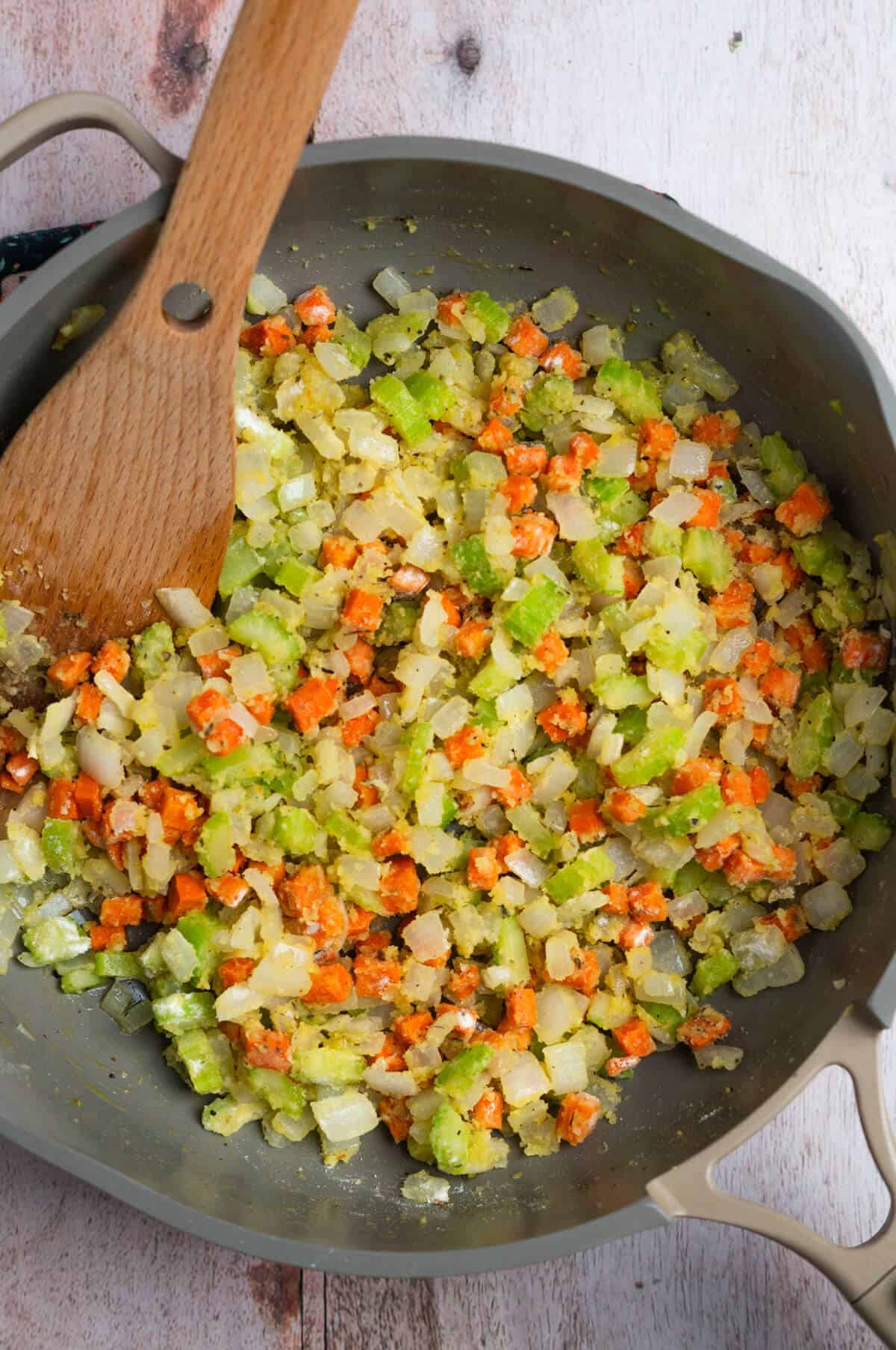 A large skillet with chopped celery, onion, carrot with spices, melted butter and flour.