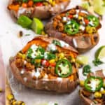 Four Mexican stuffed sweet potatoes in a line on a cutting board.