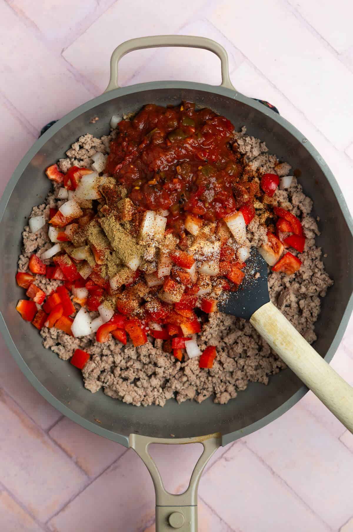A nonstick pan with cooked ground turkey with diced vegetables and spices.