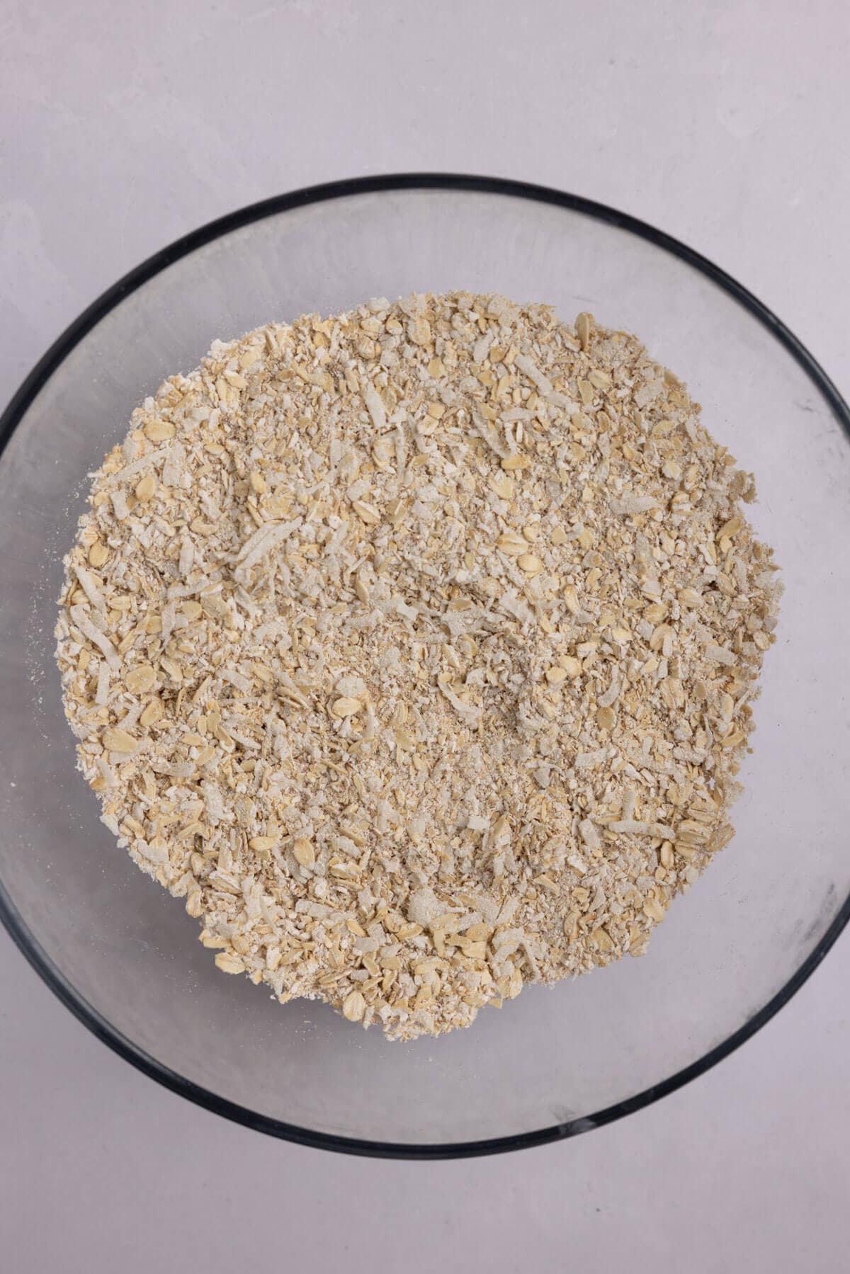 A large mixing bowl of blended oats with shredded coconut and salt.