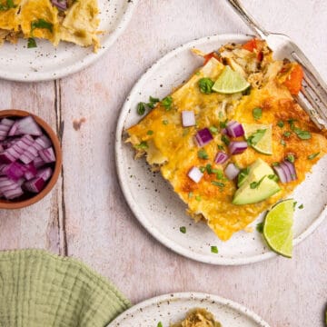 A piece of lazy enchiladas on a plate garnished with diced red onion, avocado, cilantro, and lime slices.