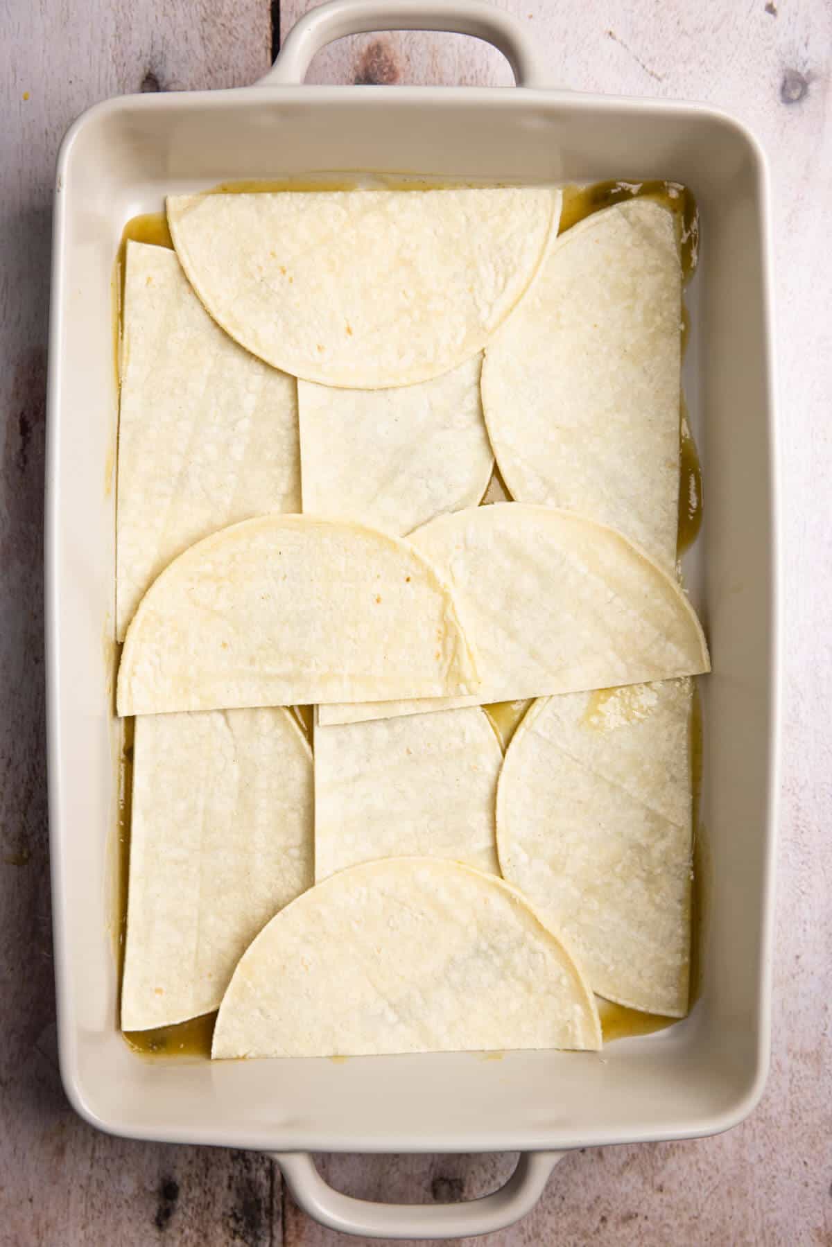 A 9x13 baking dish lined with halved corn tortillas.