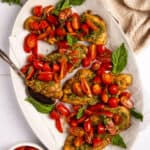 An oval platter with four pieces of pesto bruschetta chicken.