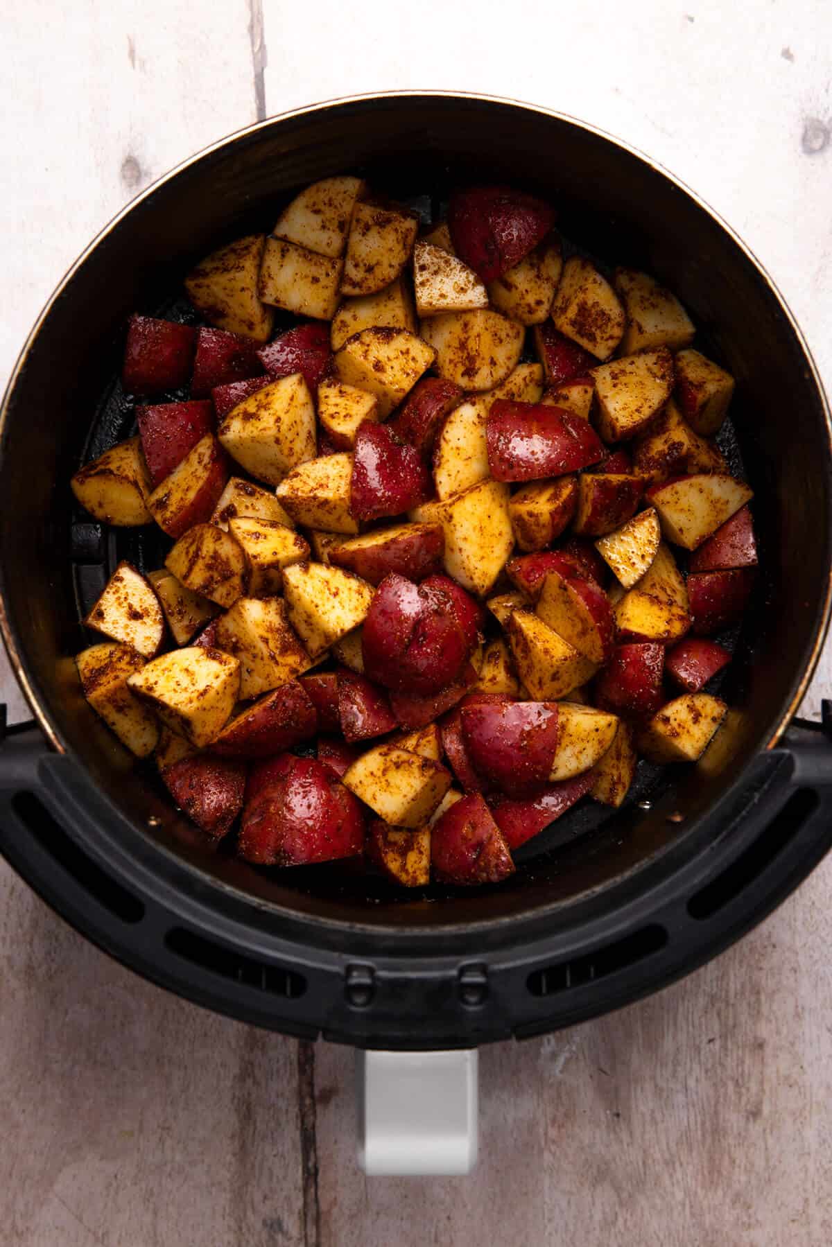 Seasoned red potatoes in an air fryer basket.