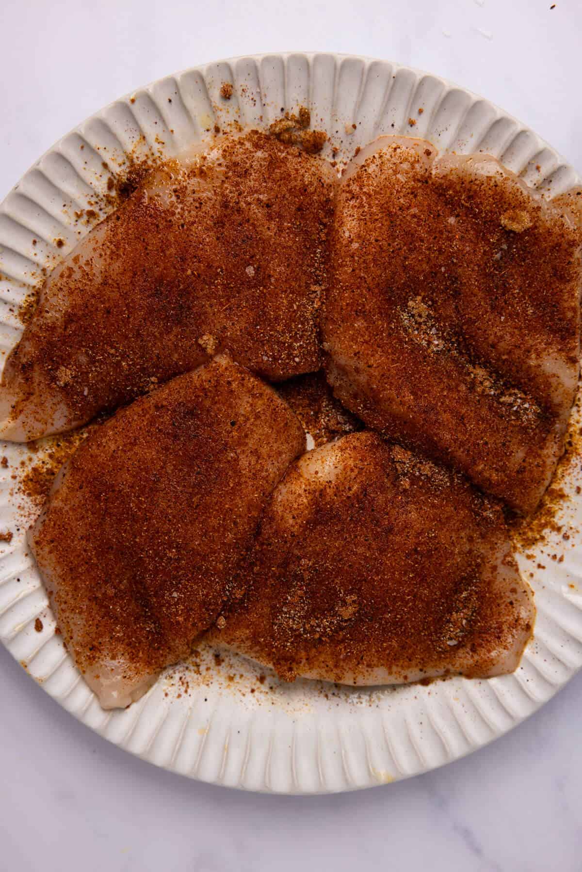 Raw chicken breasts coated with blackened seasoning.