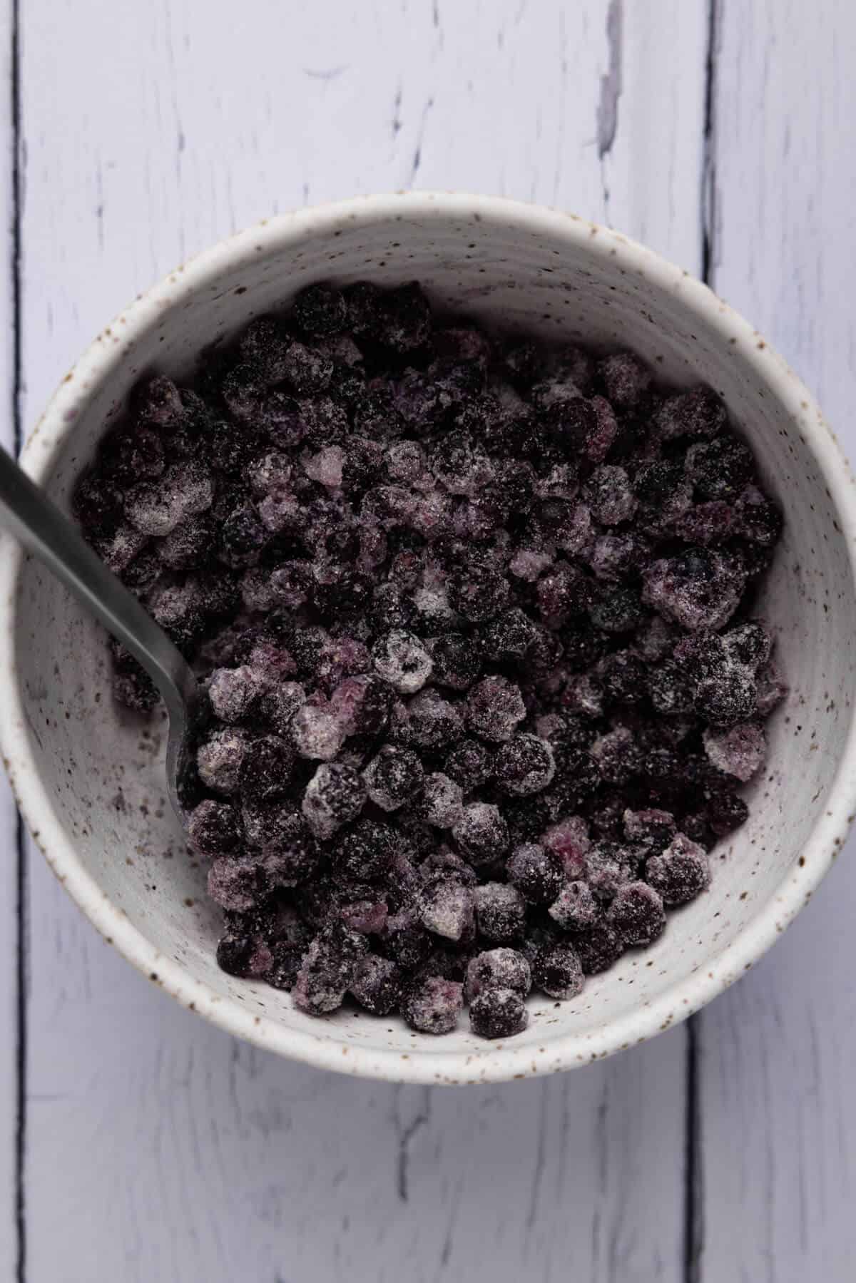 A small bowl of frozen blueberries tossed with flour.