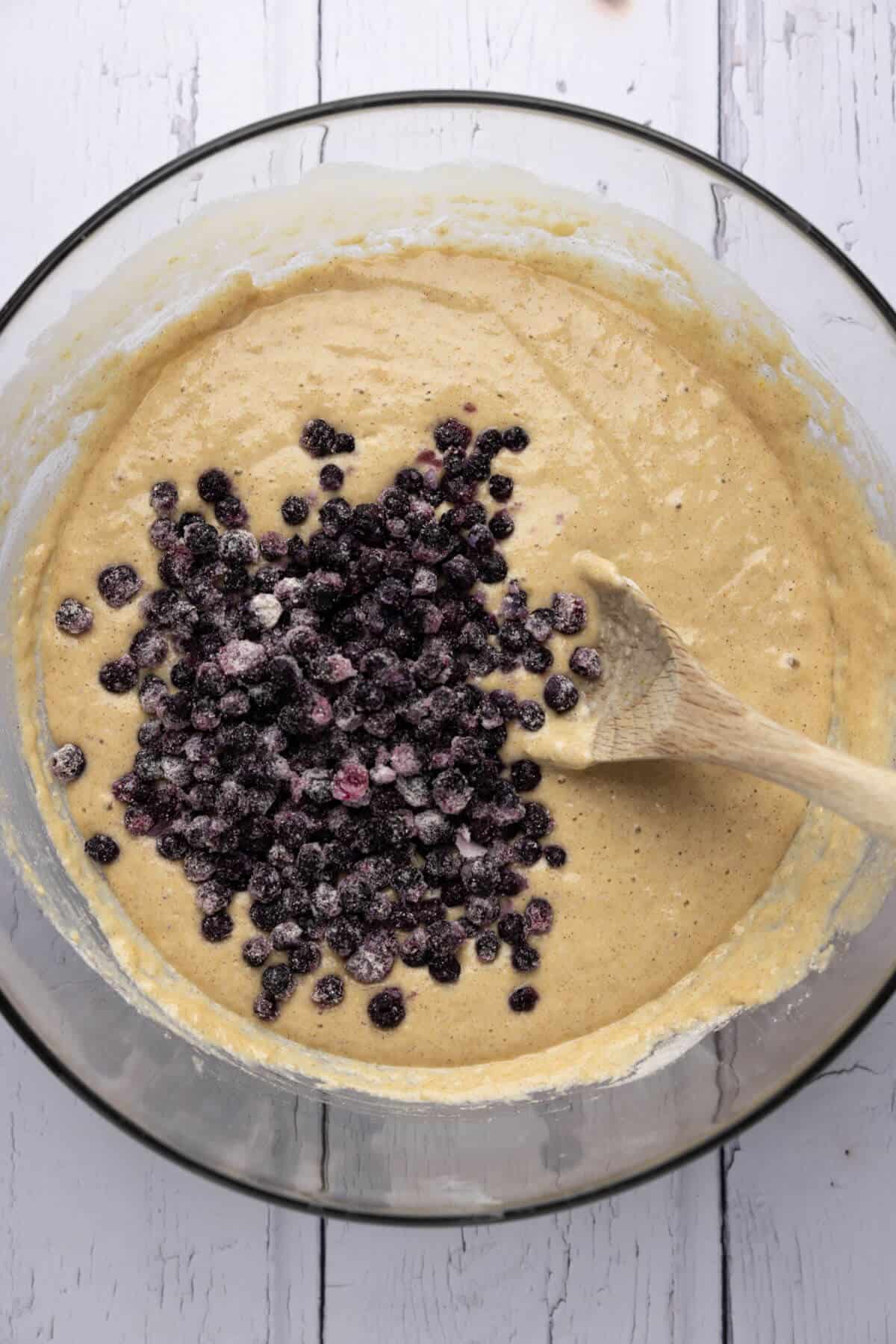 Blueberries added to the large mixing bowl of muffin batter.