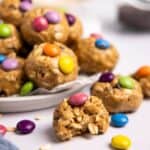 Picture of monster cookie protein balls on a plate with M&Ms around it.