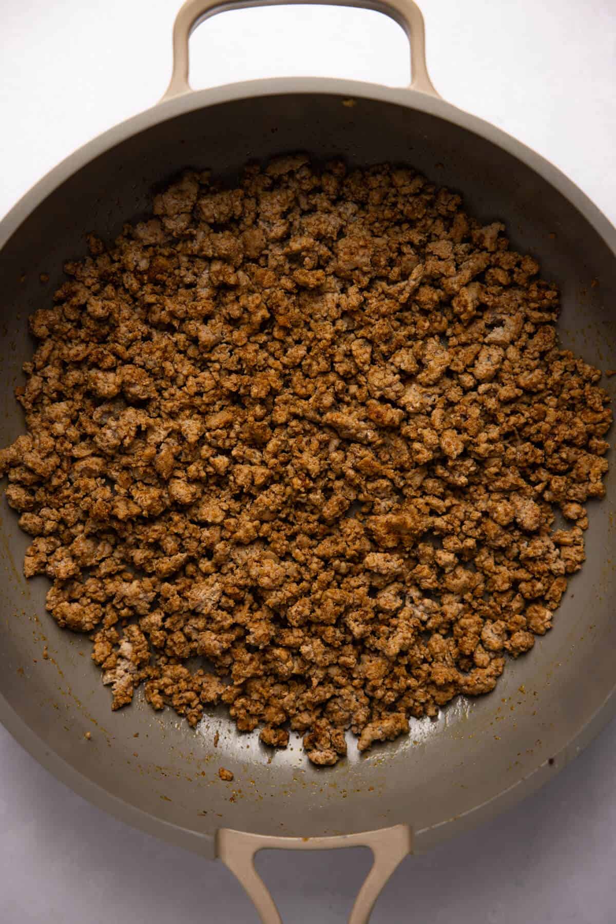 A nonstick pan with cooked and seasoned ground turkey.