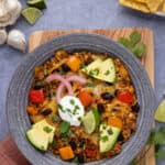 A bowl with deconstructed stuffed peppers garnished with lime, avocado, cilantro, and sour cream.