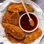 A tray of hot honey chicken tenders with a small bowl of hot honey.