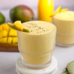 A centered photo of a mango protein smoothie in a glass, topped with fresh mango and chia seeds.