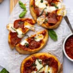 Three pepperoni flatbreads on a wooden serving board.