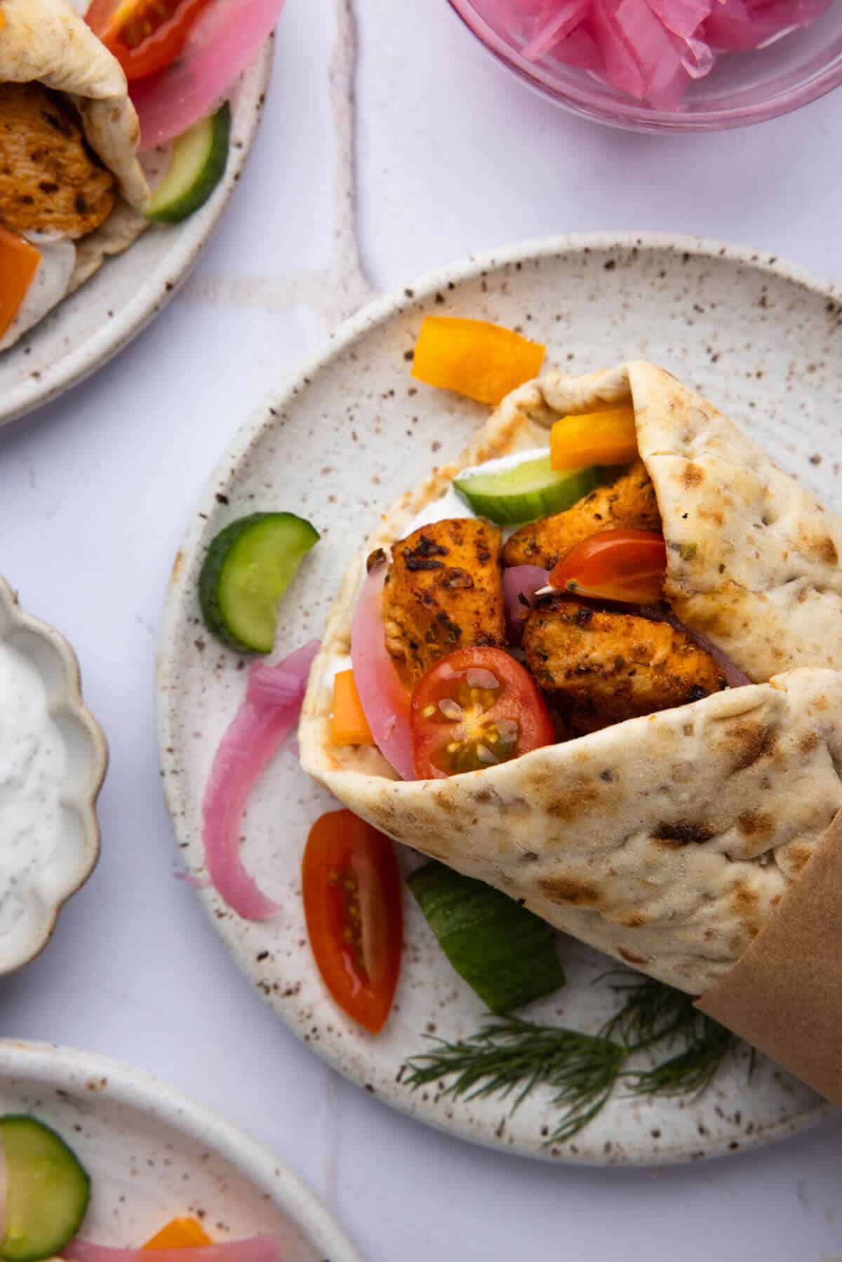 An overhead shot of a plate with an assembled Greek chicken wrap.