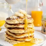 A stack of banana coconut pancakes with coconut syrup.