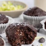 A shot of a chocolate zucchini muffin with a bite taken out of it to show melted chocolate.