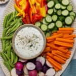 Overhead shot of a large serving board of chopped vegetables with cottage cheese ranch dressing dip.