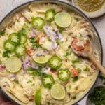 Overhead shot of white chicken enchilada skillet topped with jalapeño and lime.