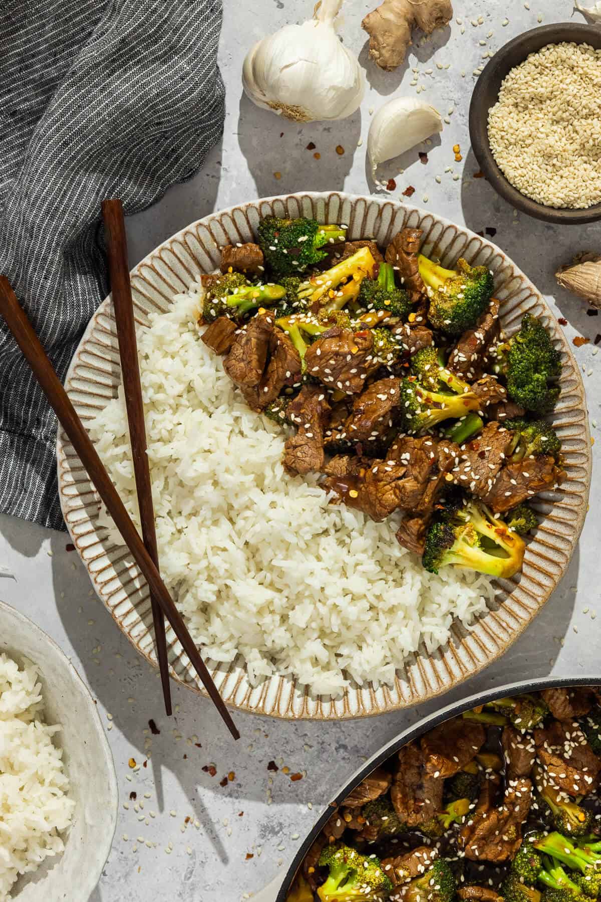 Plate of beef and broccoli served with white rice and chopsticks.
