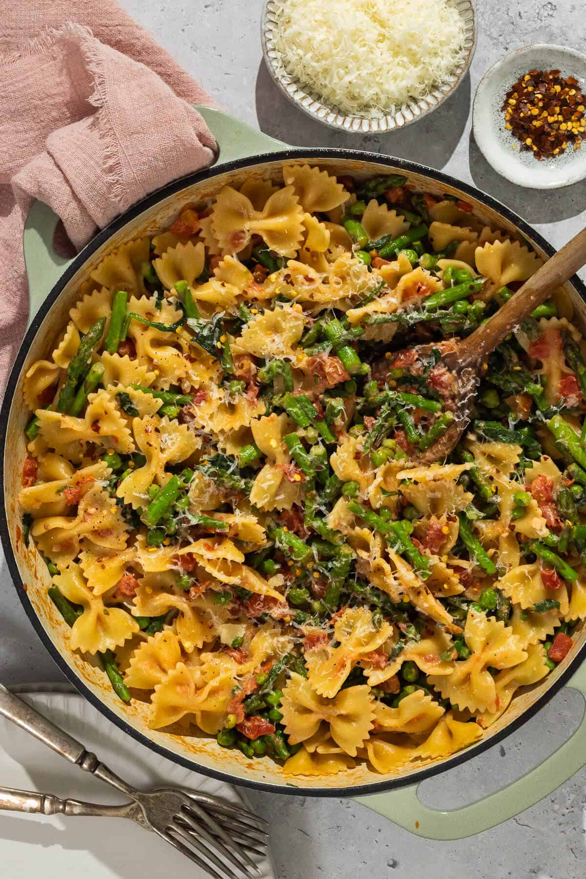 Bow tie vegetable pasta in a large pot with a wooden serving spoon.