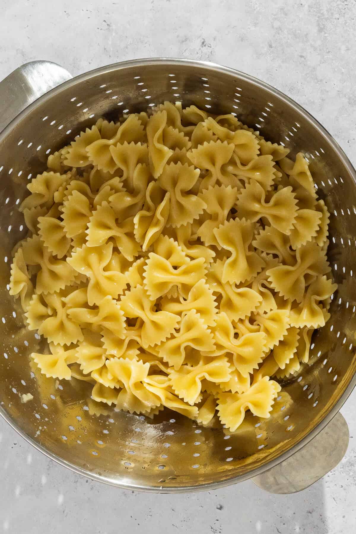 Colander with cooked bowtie pasta.