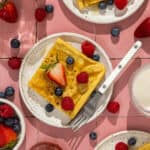 Three plates with pieces of German pancakes topped with berries.