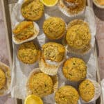 A sheet pan with cooked lemon poppyseed zucchini muffins scattered across.