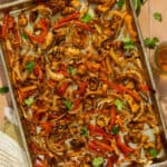 A sheet pan with prepared chicken fajitas.