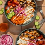 Two buffalo chicken bowls with ranch dressing and buffalo sauce drizzled over the top.