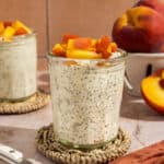 A glass jar of peach overnight oats topped with peaches.