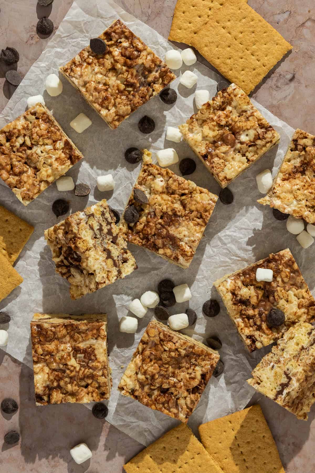 Squares of s'mores Rice Krispies scattered across parchment paper.
