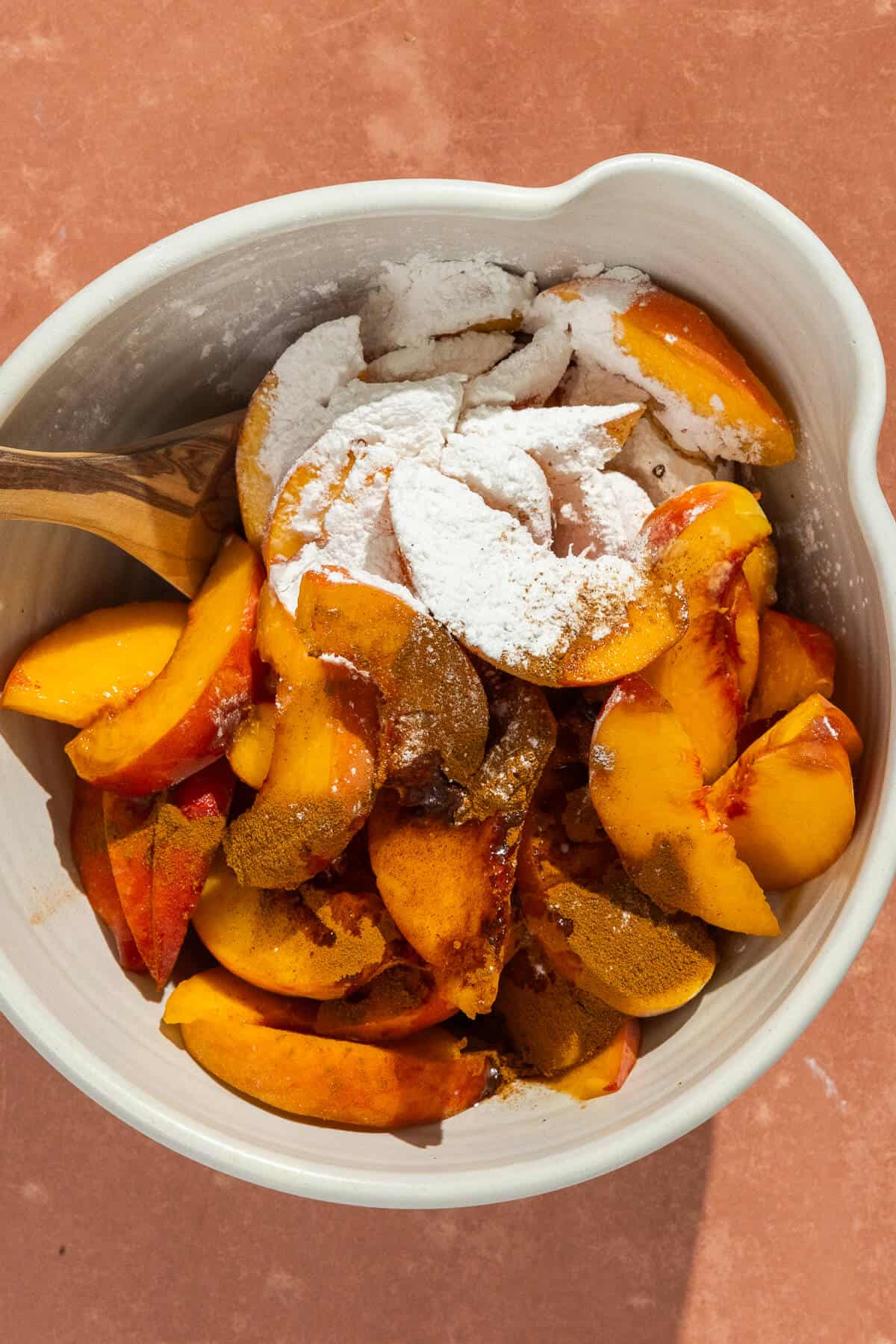 A large mixing bowl with the peach mixture ingredients prior to being combined.