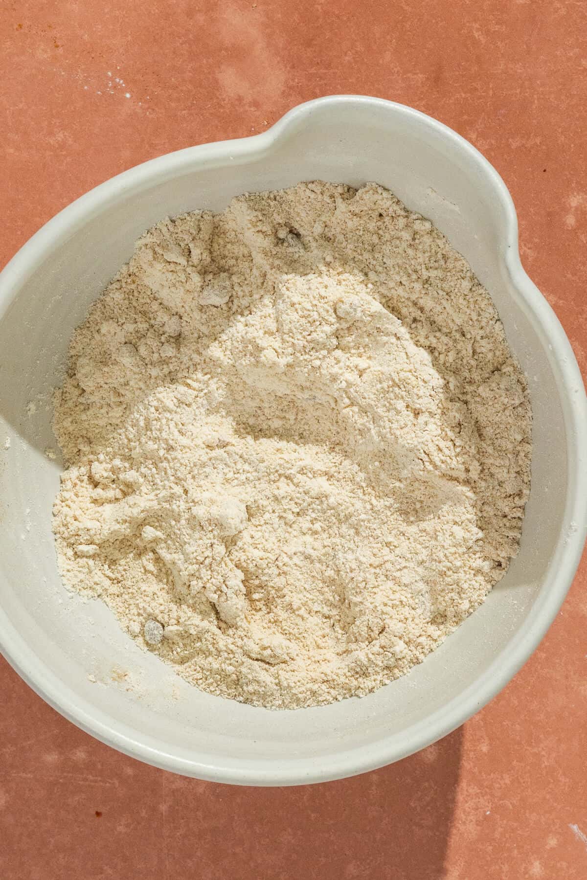 A mixing bowl with the ingredients for the crumble topping after being mixed.
