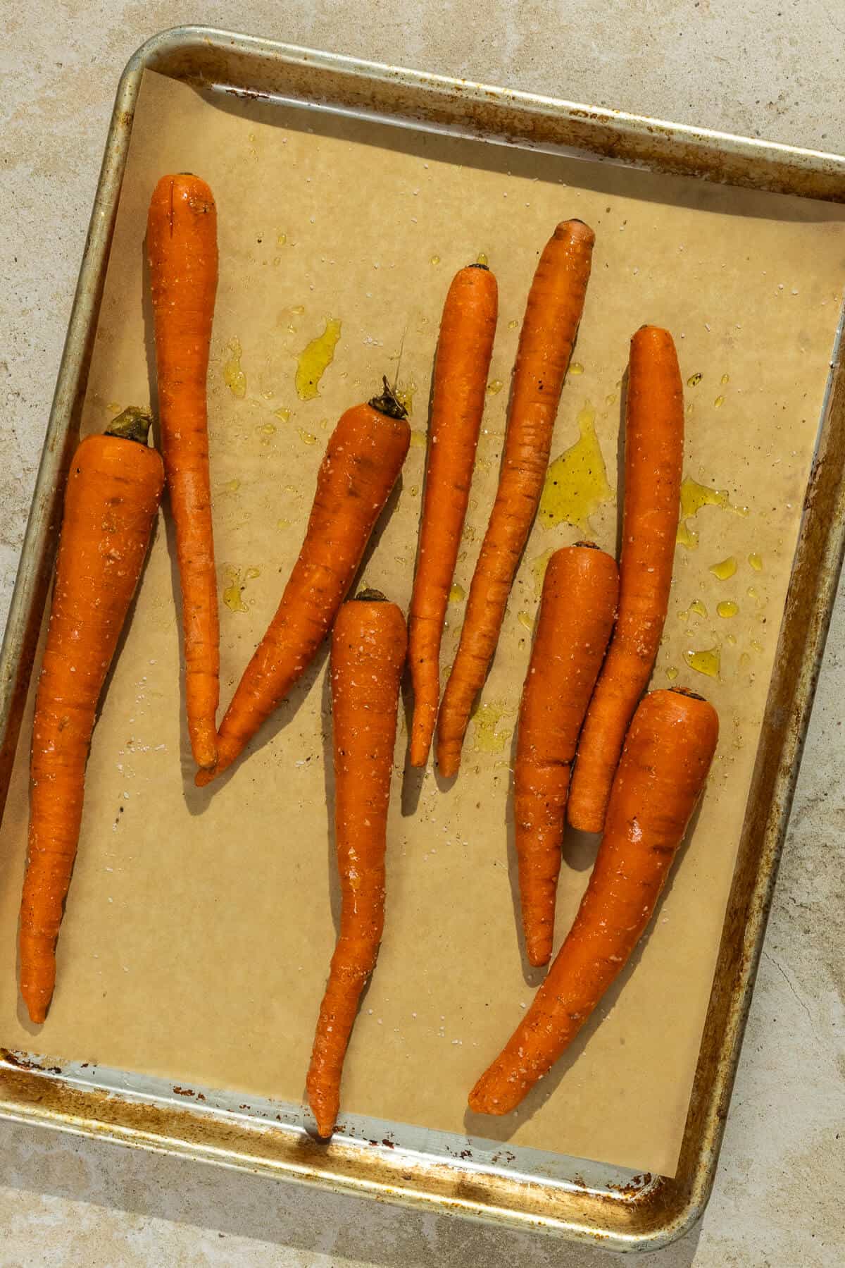 Parchment lined baking sheet with carrots prior to roasting.